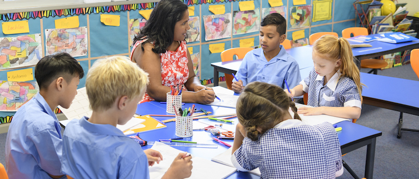 “teacher-and-students-working-at-desk-in-classroom“