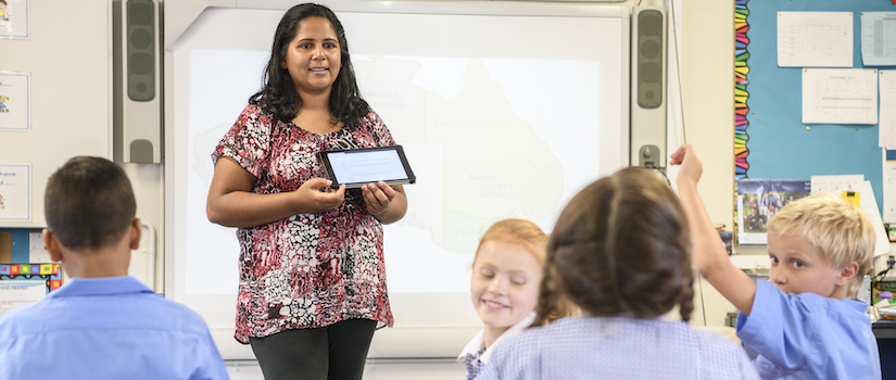 “teacher-with-ipad-at-the-front-of-classroom“