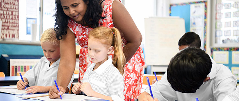 “teacher-at-desk-in-classroom“