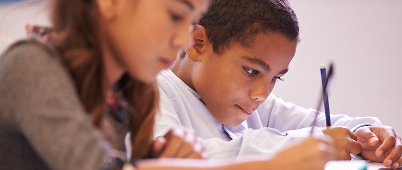 “student-writing-at-desk-in-classroom“